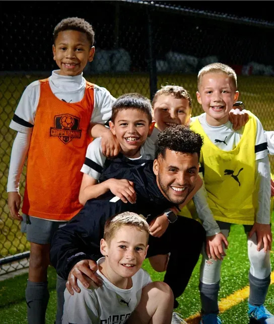 Coppermine Soccer Club's coach surrounded by happy youth club soccer players.