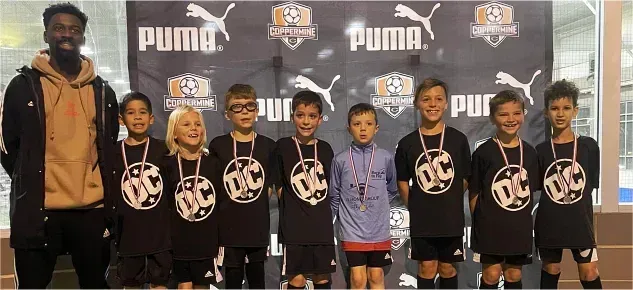 A group of young boys are posing for a picture in front of a puma banner.