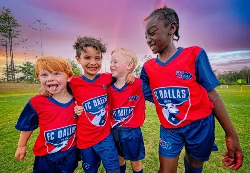 A group of young boys are posing for a picture on a soccer field.