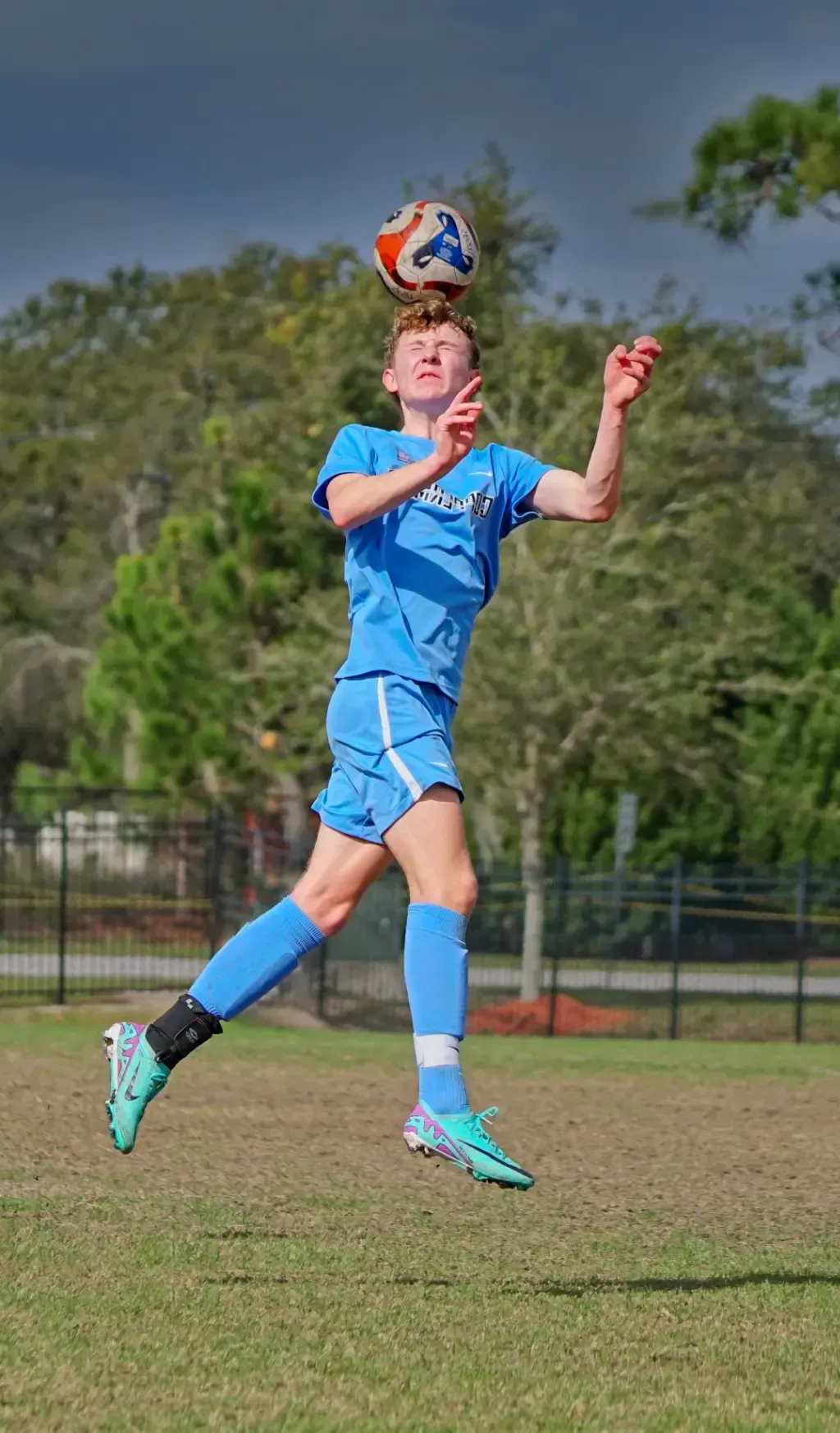 A young boy is heading a soccer ball in the air.