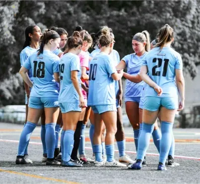 a group of Coppermine United female soccer players are huddled together 