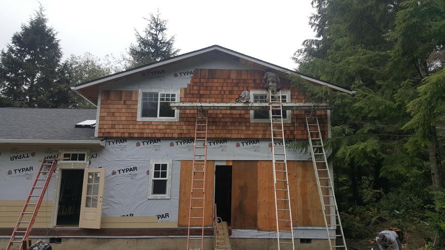 A house is being remodeled with wood siding and a roof.