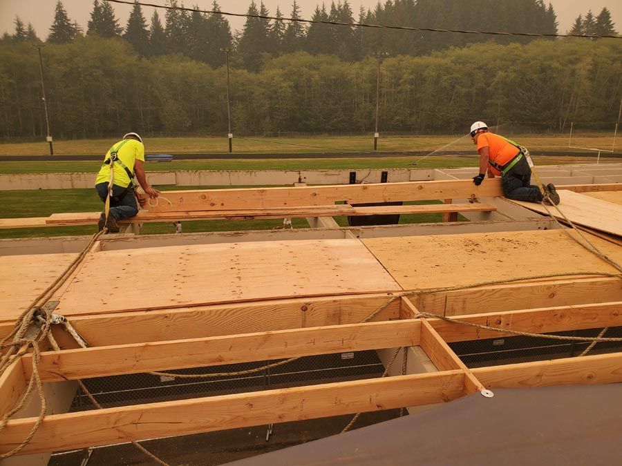 Two construction workers are working on the roof of a building