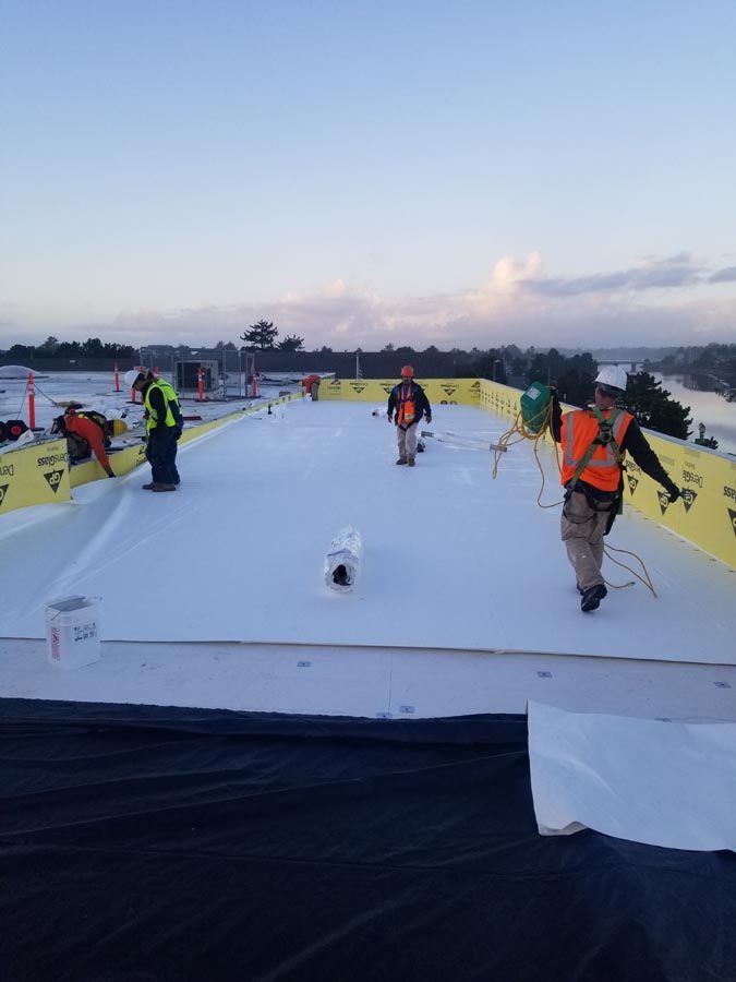 A group of construction workers are working on a white roof.
