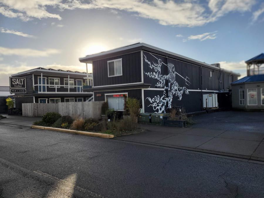 A black and white building with a mural on the side of it.