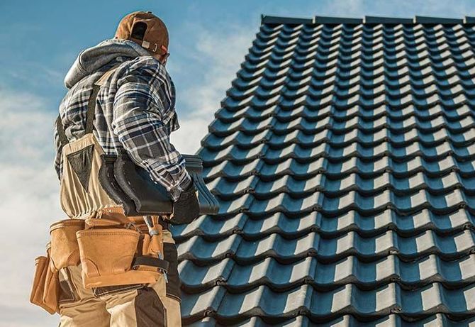 A man is standing on top of a tiled roof.