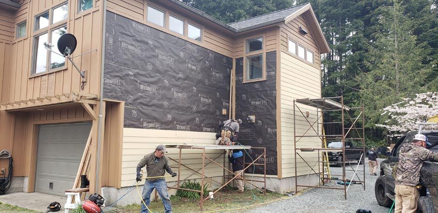 A group of people are working on the side of a house.
