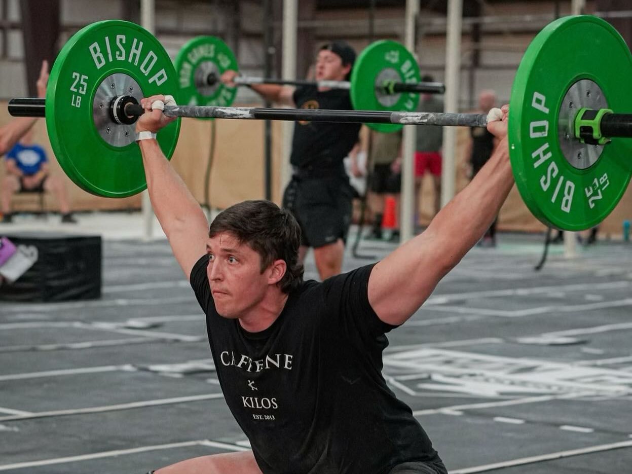 A man in a black shirt is lifting a barbell over his head.