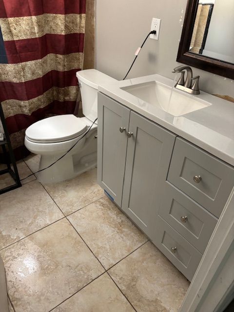 Bathroom with a toilet, vanity with sink, and American flag shower curtain.