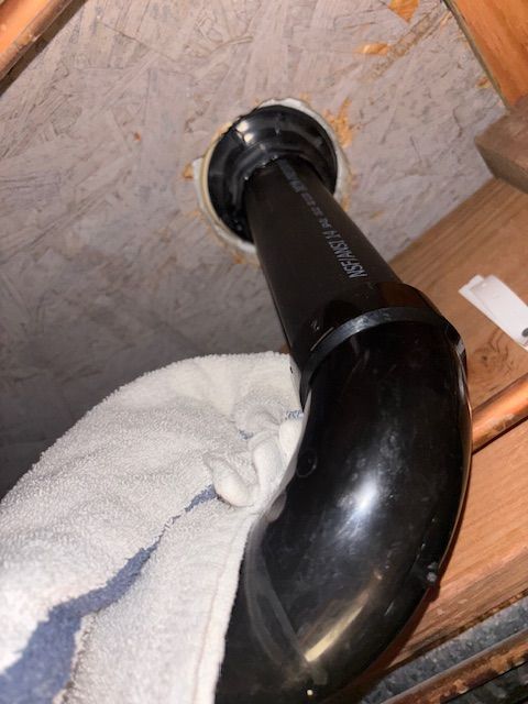 Black pipe connected to ceiling, passing through hole. A white towel is partially visible below the pipe.