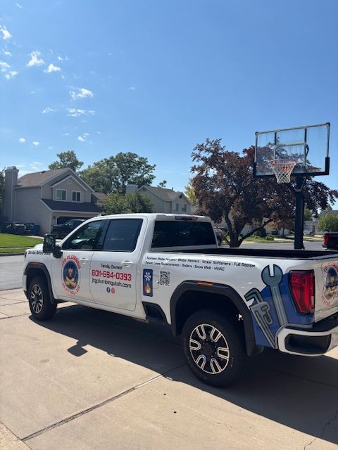 White work truck with service logo parked on a driveway in front of a house, a basketball hoop is in the background.