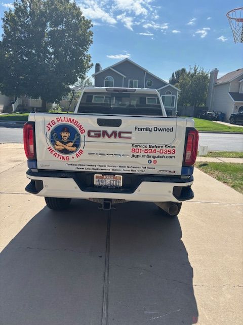 White GMC truck with company logo parked in front of a house.