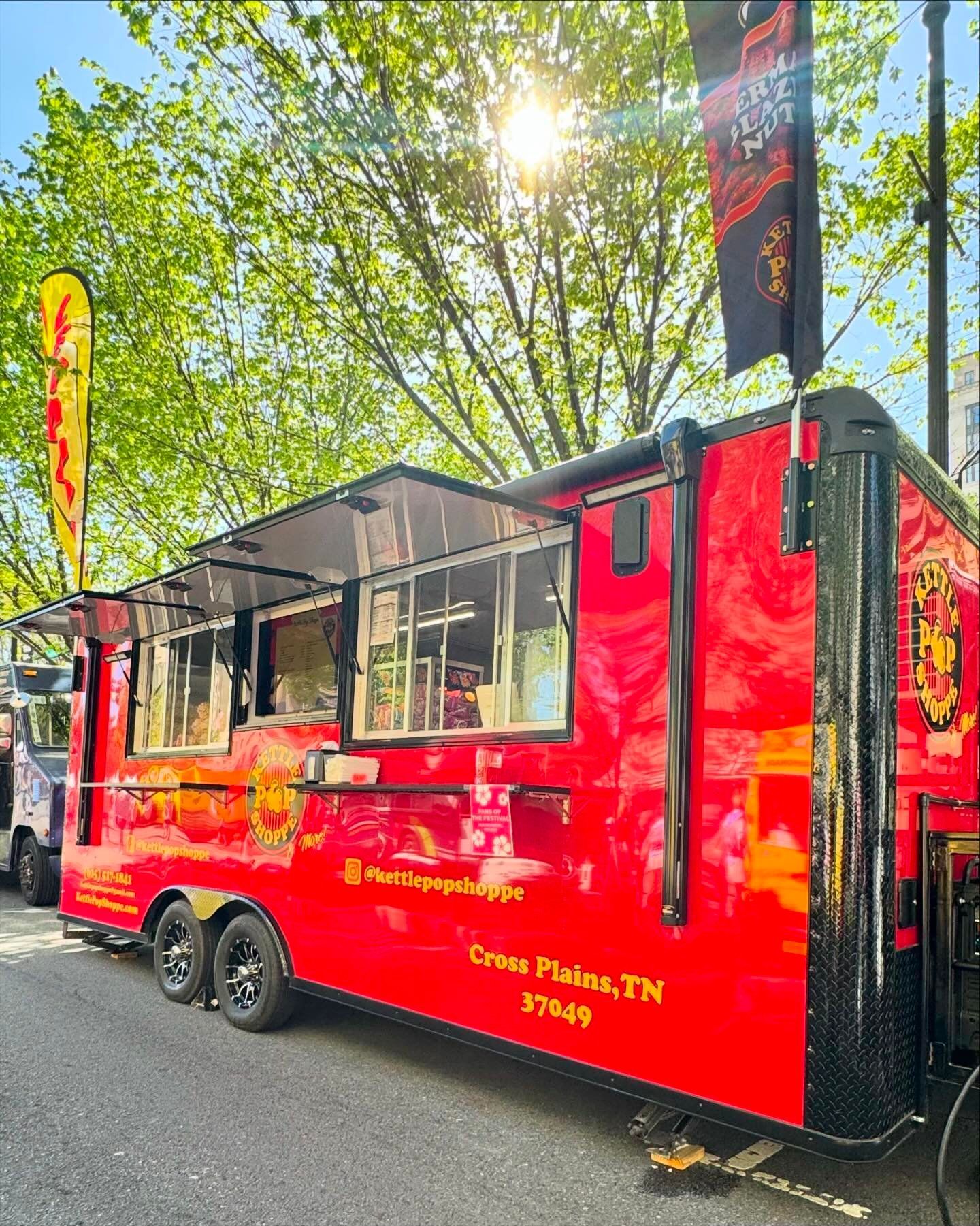A red food truck is parked on the side of the road.