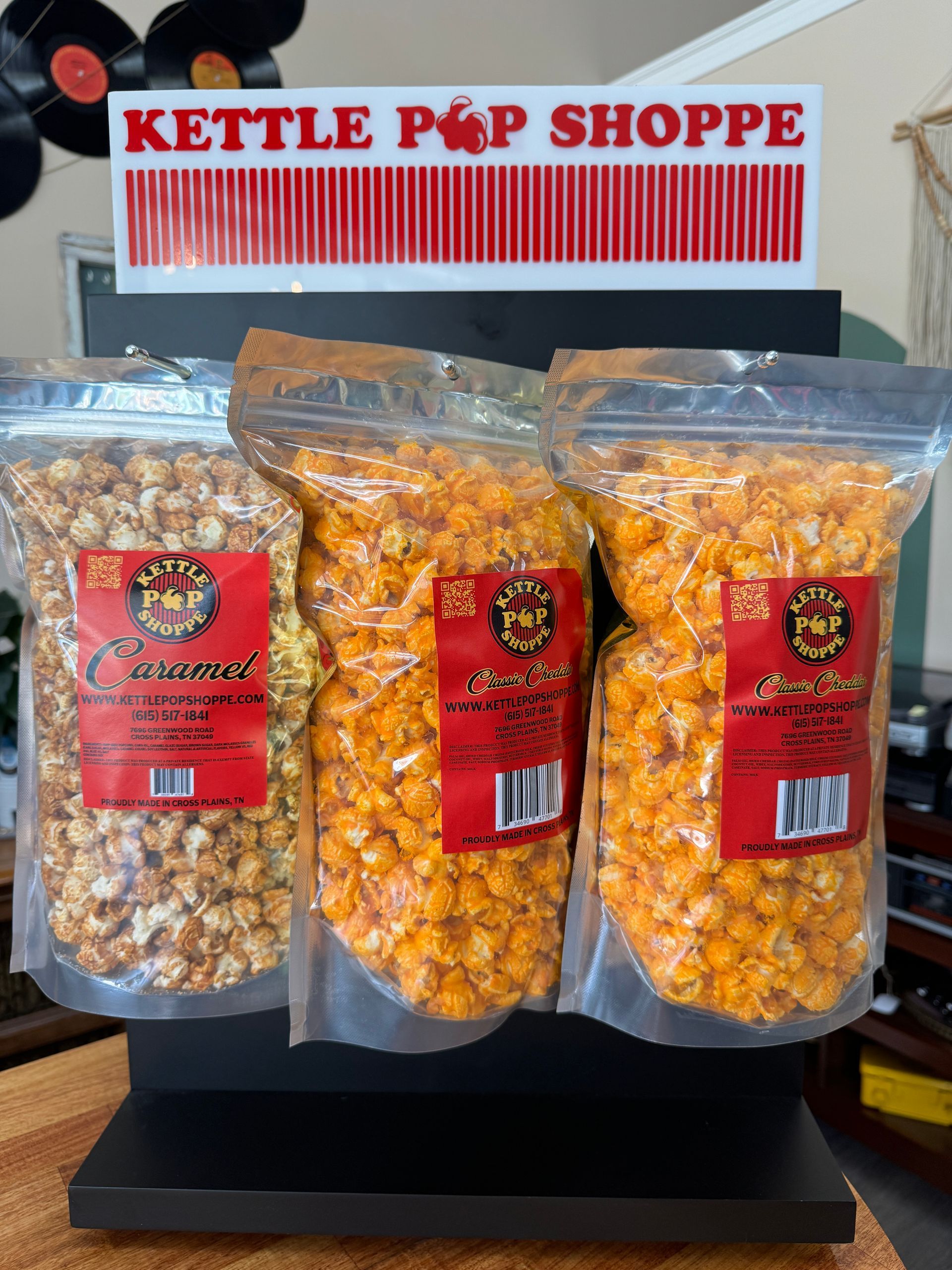 Bags of popcorn are lined up on a shelf in front of a window.