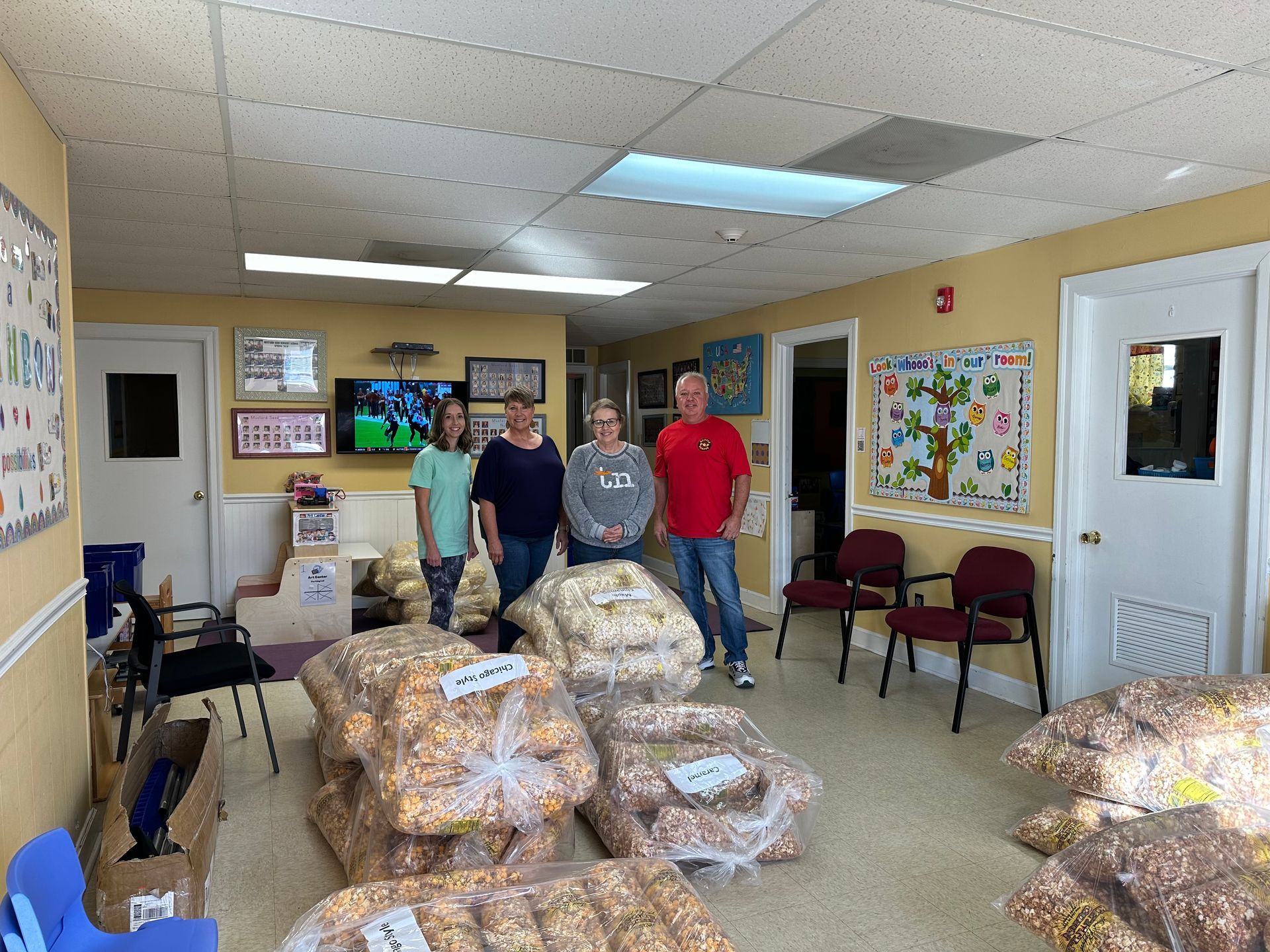 A group of people are standing in a room filled with bags of food.