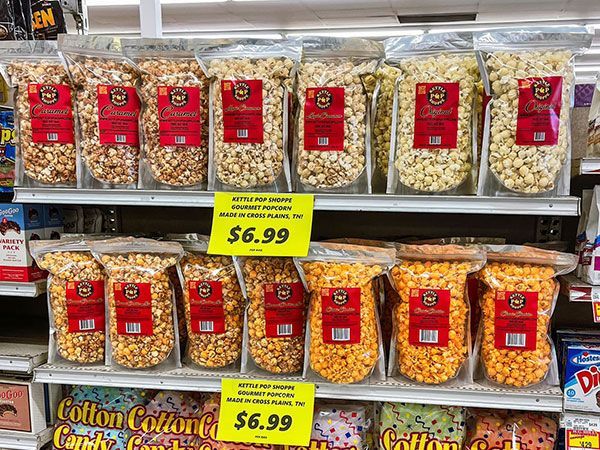 Bags of popcorn are lined up on a shelf in a store.