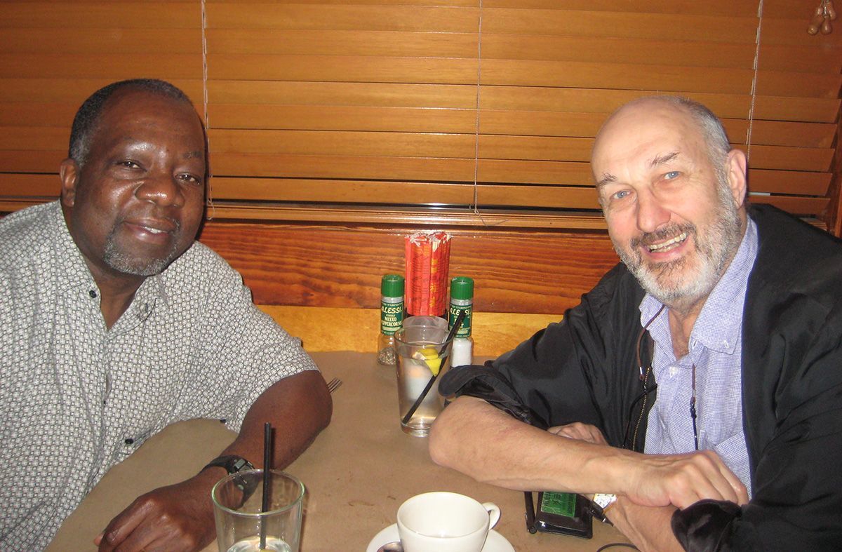 Two men are sitting at a table with a cup of coffee