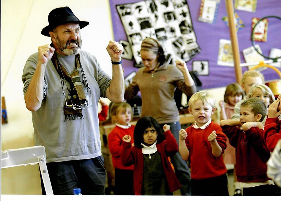 A man in a hat is standing in front of a group of children