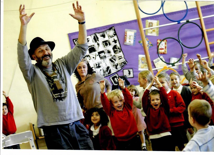 A man in a hat is standing in front of a group of children