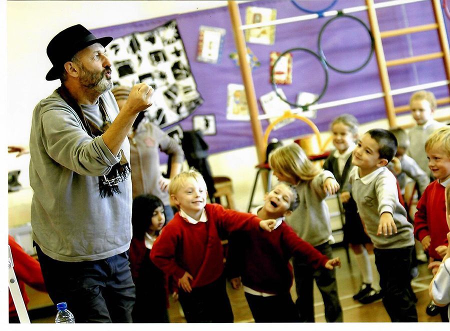 A man singing into a microphone in front of a group of children