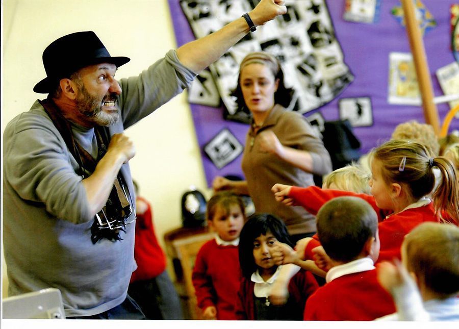 A man in a hat stands in front of a group of children