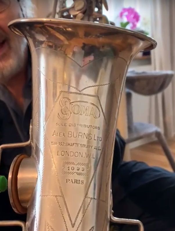 A man is holding a saxophone that says coma on it