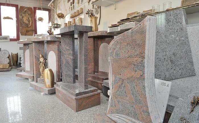 Una sala espositiva con diverse lapidi e monumenti in granito nelle tonalità del grigio, del marrone e del rosa.