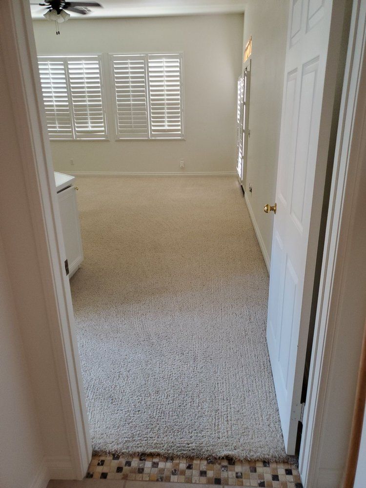 A hallway in a house with a carpeted floor and a ceiling fan.
