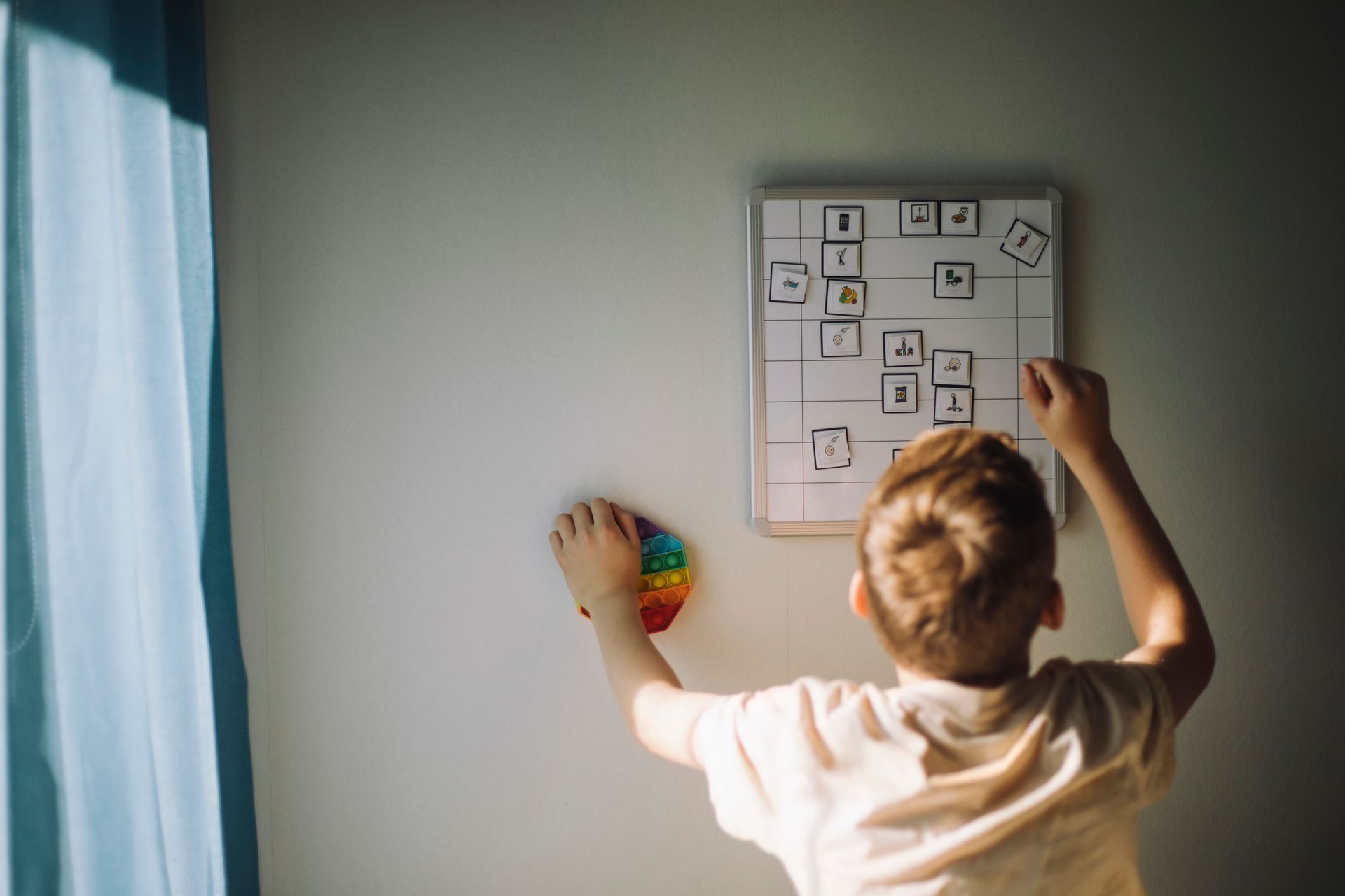 A young boy is playing with a toy on a wall.