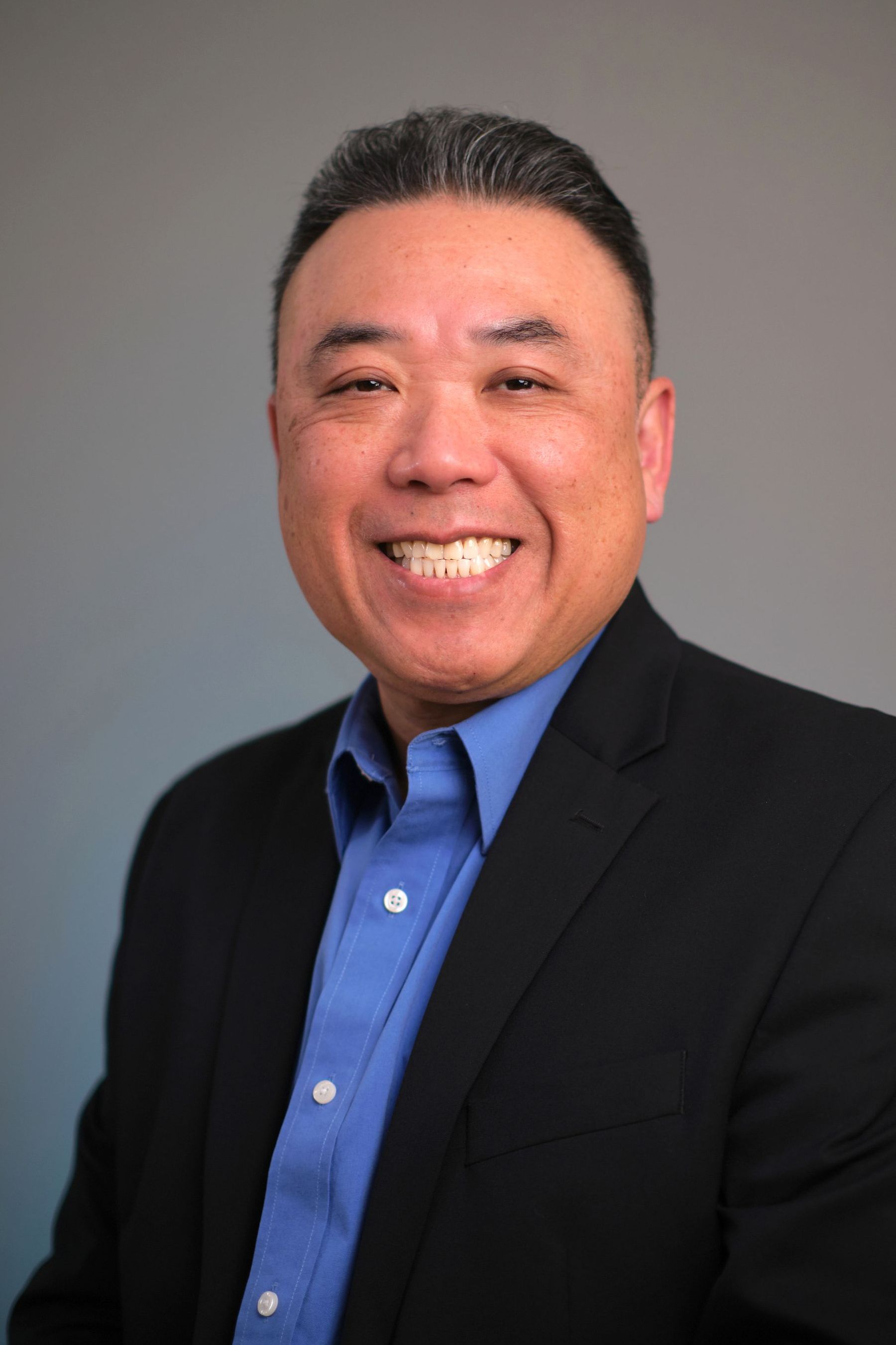 A man in a suit and blue shirt is smiling for the camera.