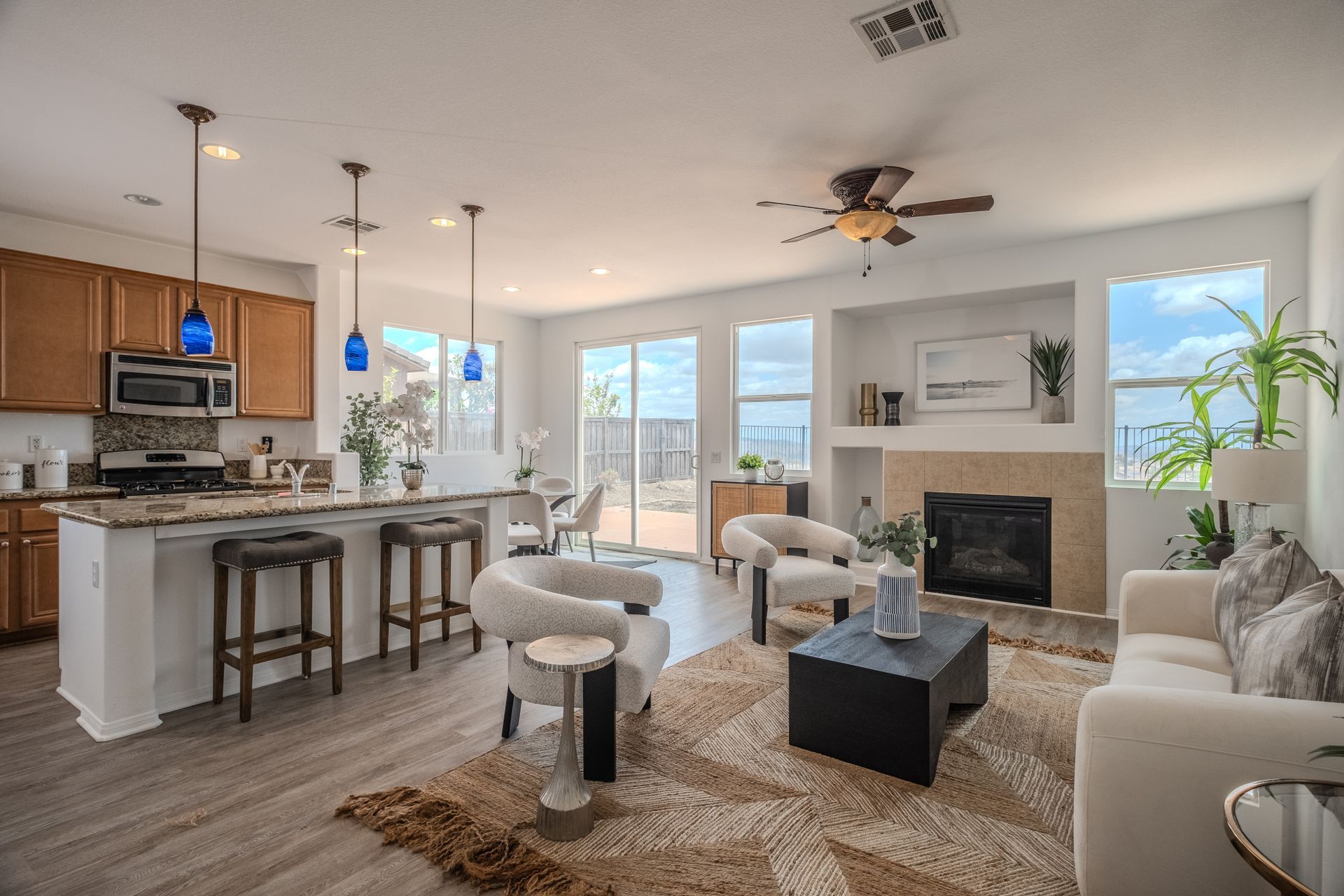 Open-concept living space with kitchen, living area, and dining, featuring light wood floors and neutral furniture.