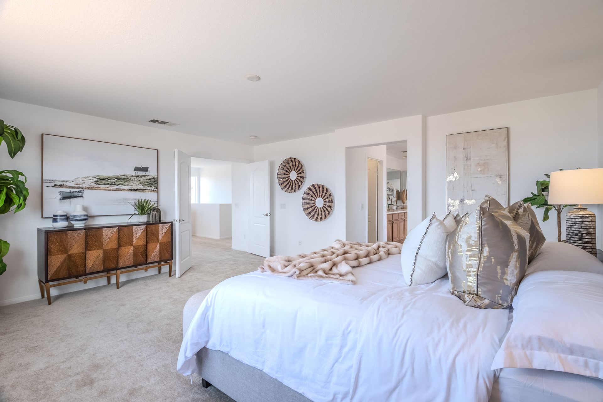 Spacious bedroom with a bed, dresser, art, and doorway leading to the spacious loft.