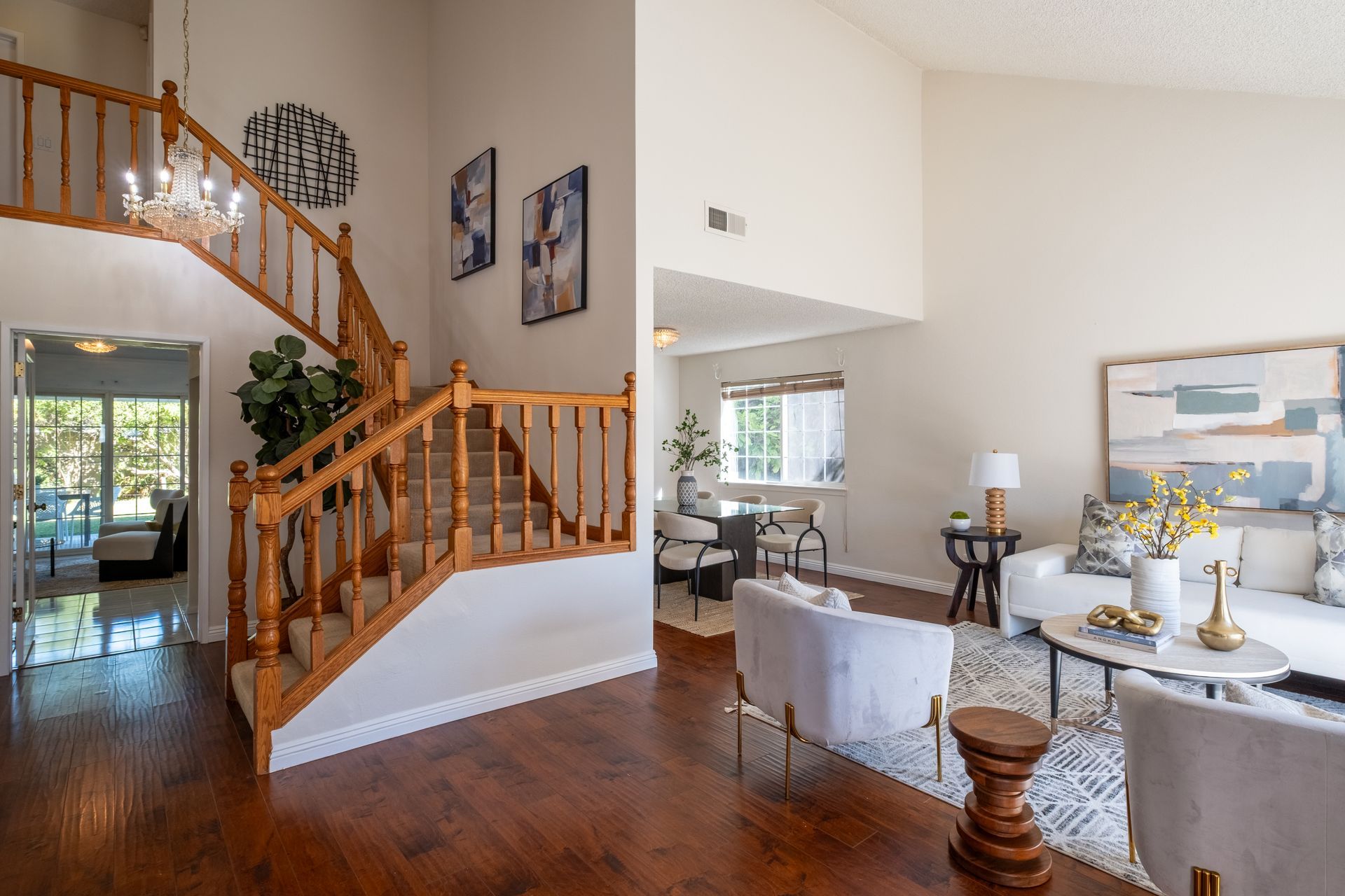 Interior with staircase and living room, featuring wood floors, neutral walls, and modern furniture.