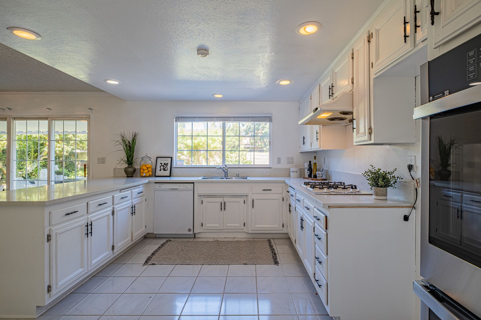 White kitchen with island, cabinets, appliances, and large window.