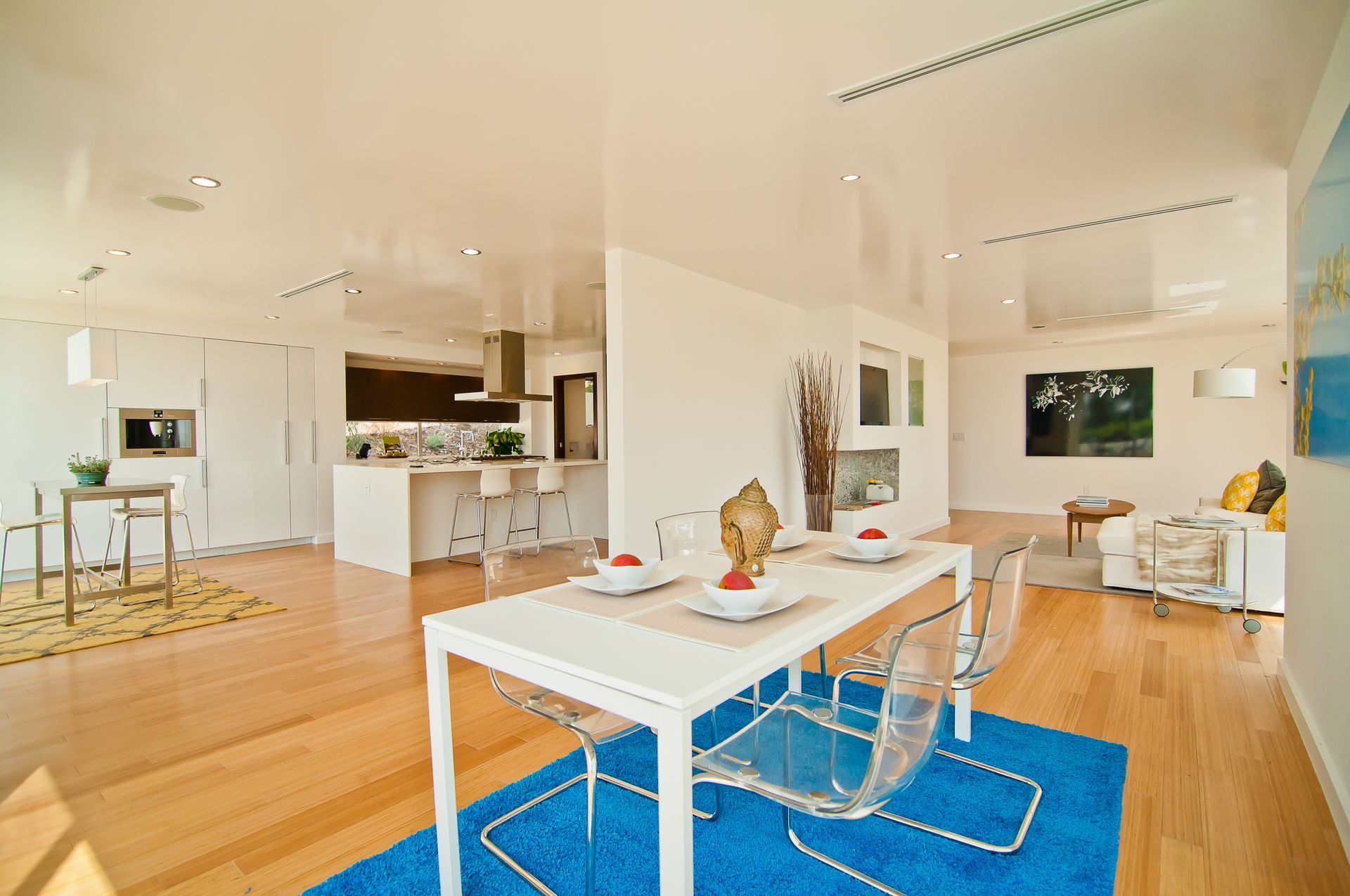 A dining room with a table and chairs and a blue rug.