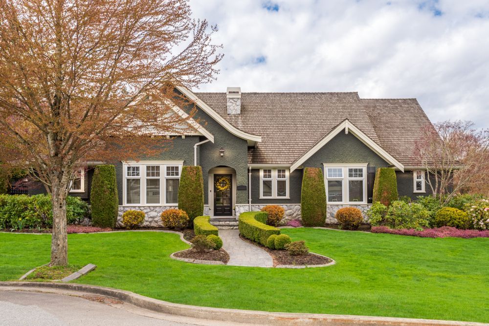 Green house with stone accents, manicured lawn, and walkway leading to the front door.