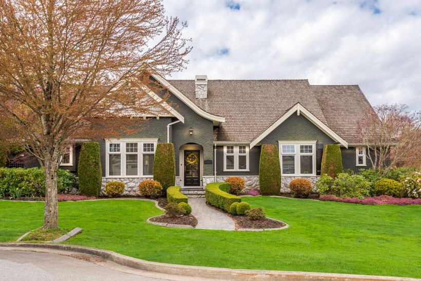 Green house with stone accents, manicured lawn, and walkway leading to the front door.
