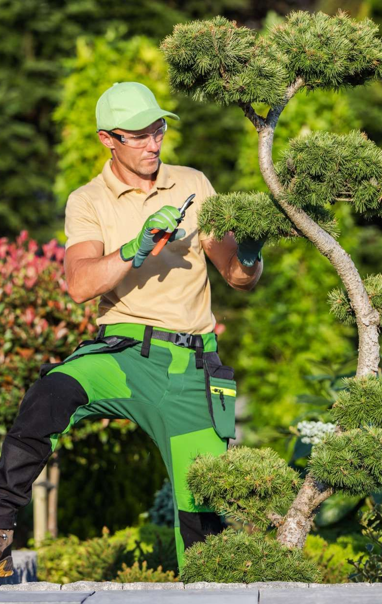 Construction of a paved walkway with dark gray square pavers, mallet, and gravel base.