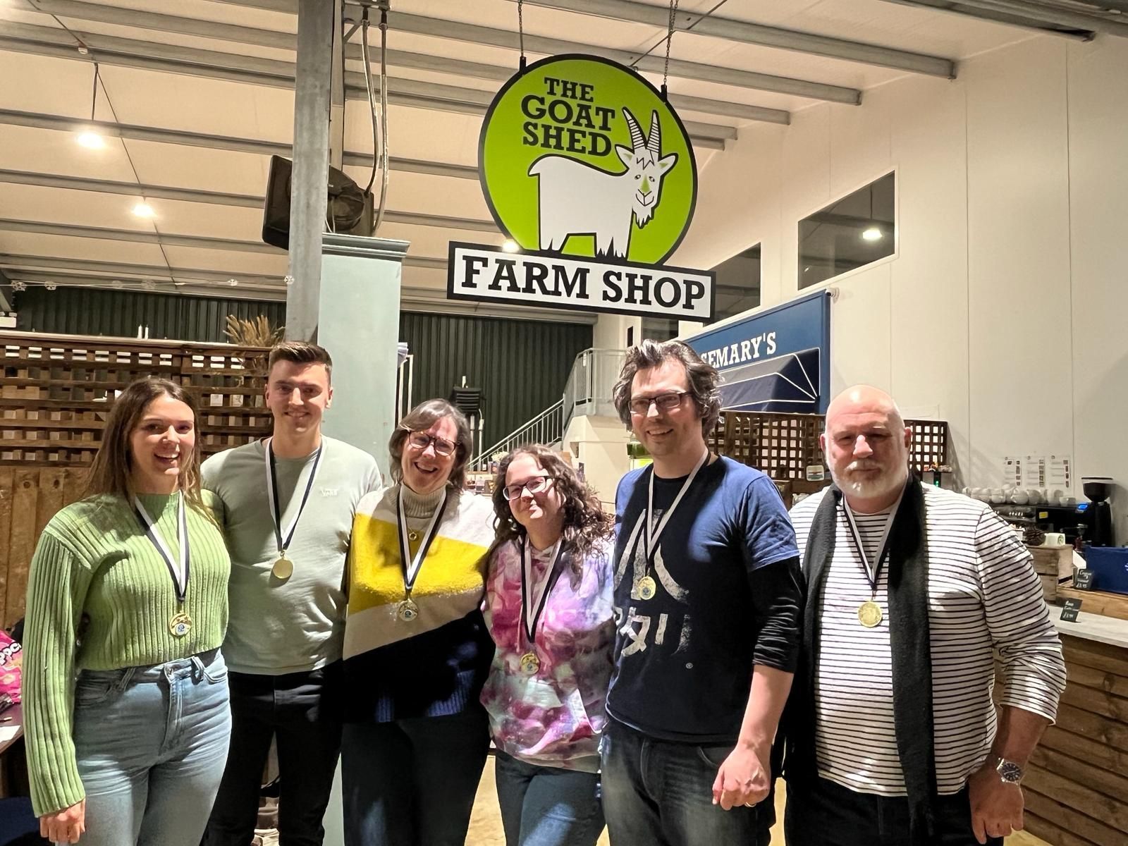 Six people with medals pose in front of a 