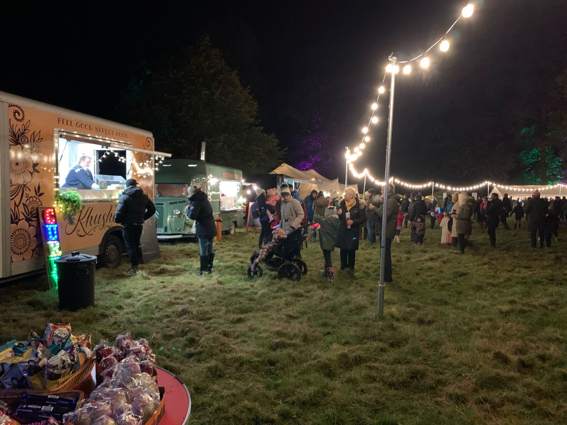 Food trucks and crowds gathered at a night market under string lights.