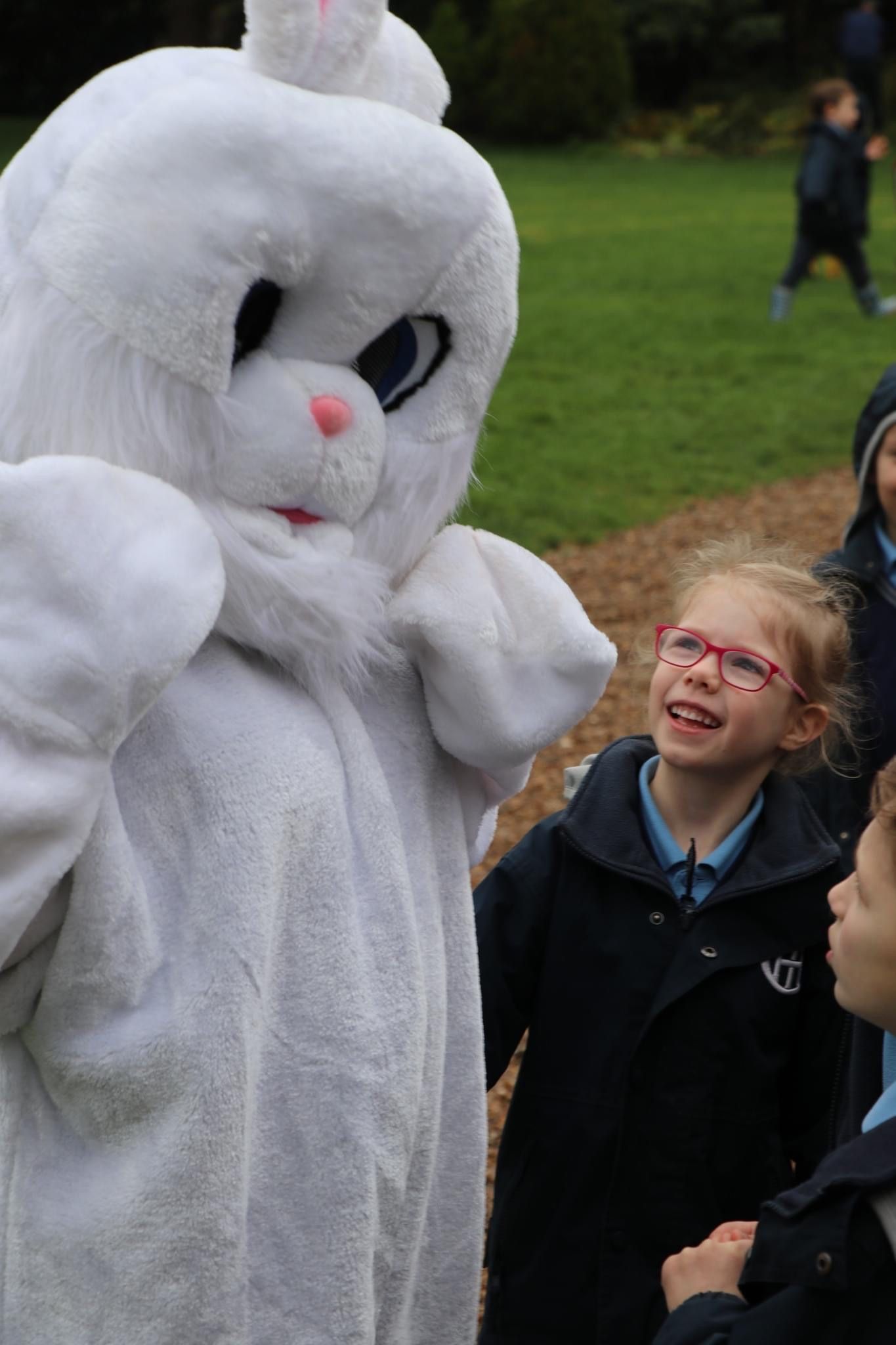 Easter Bunny costume interacting with excited children outdoors.