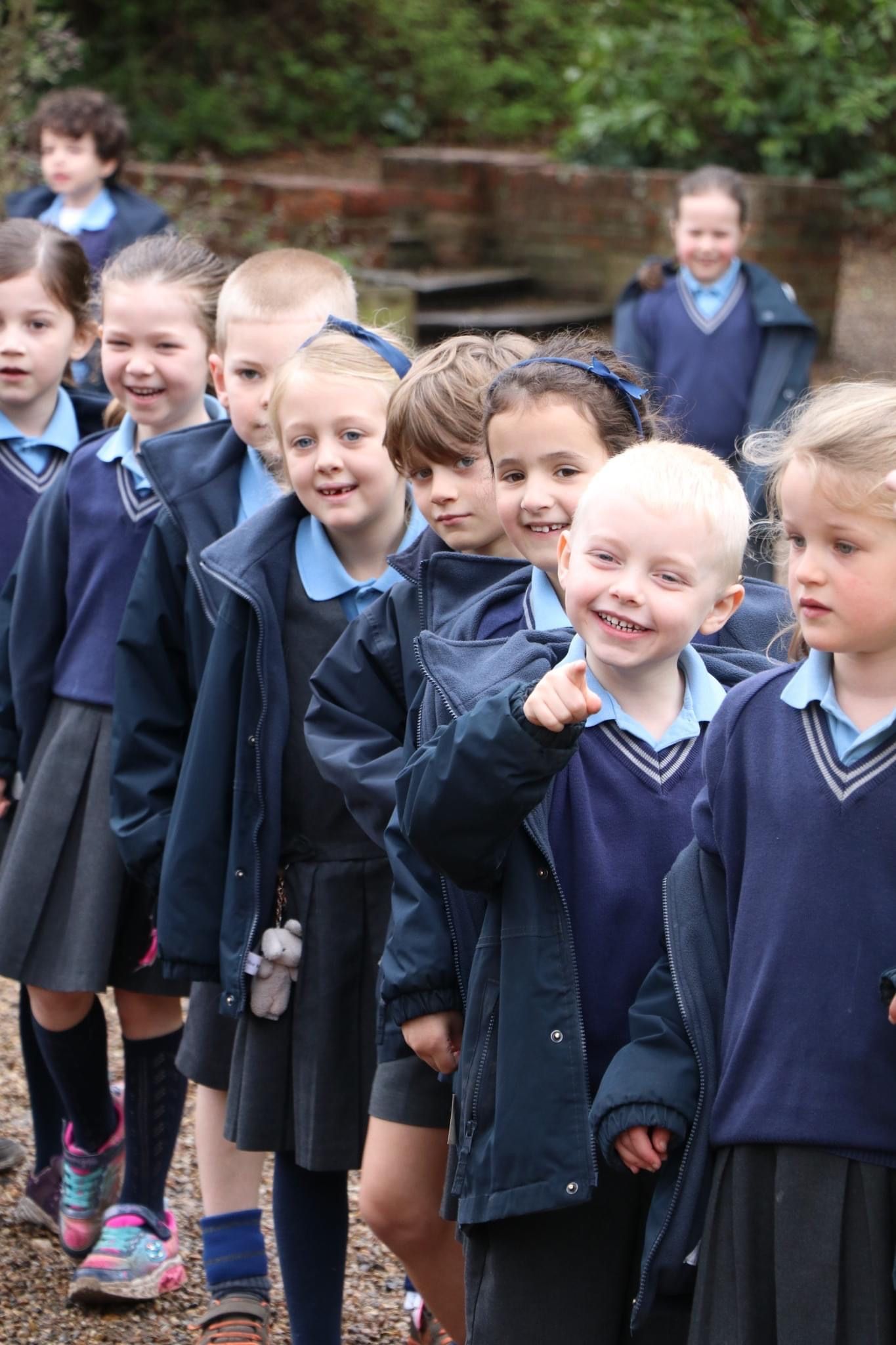 Children in school uniforms lined up outdoors, smiling.