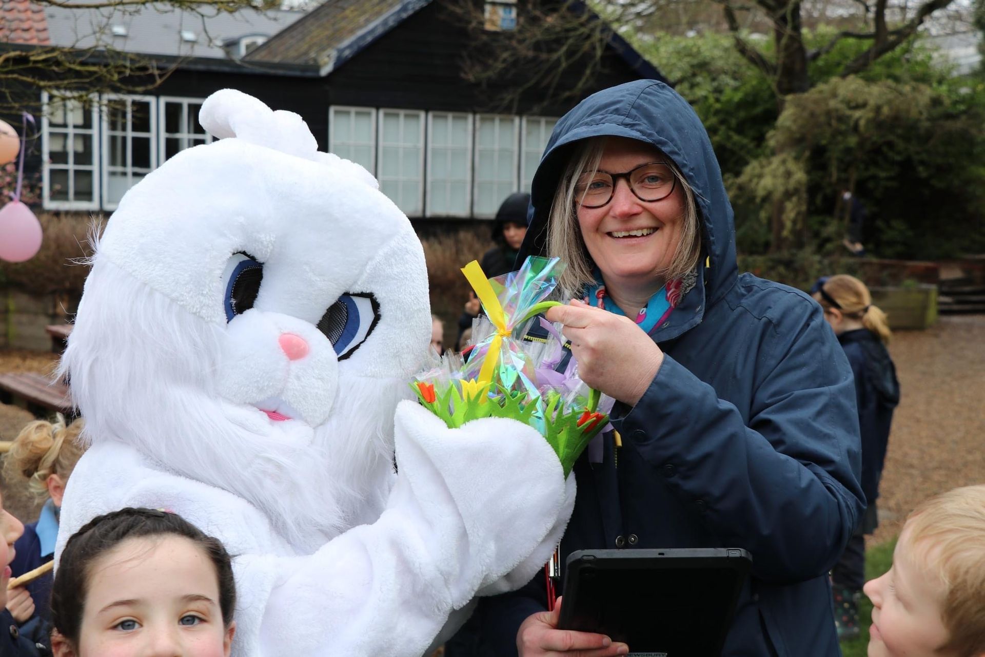 Easter Bunny with woman holding basket, smiling, outdoor setting.