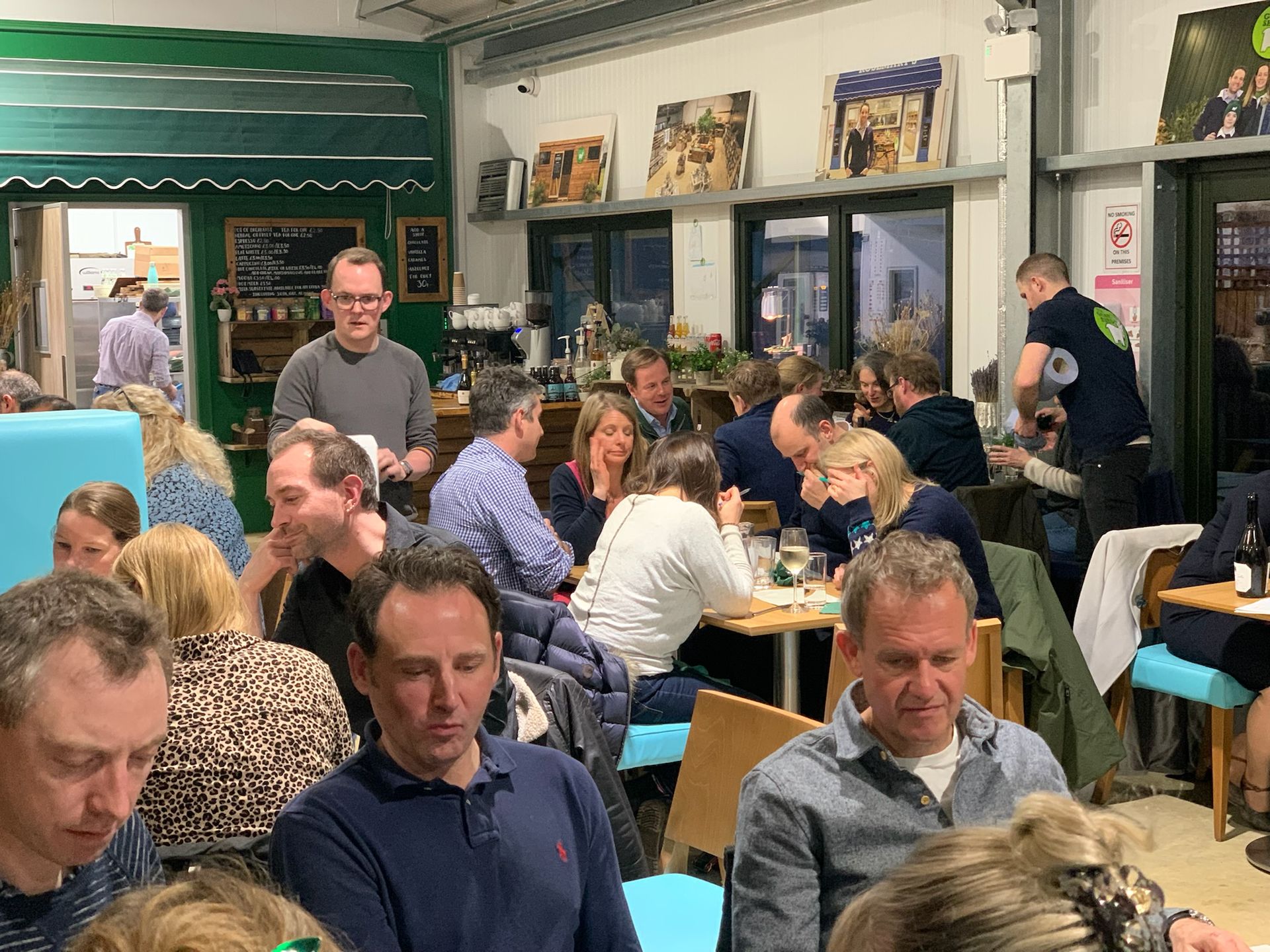 People dining in a brightly lit cafe, some looking at the camera.