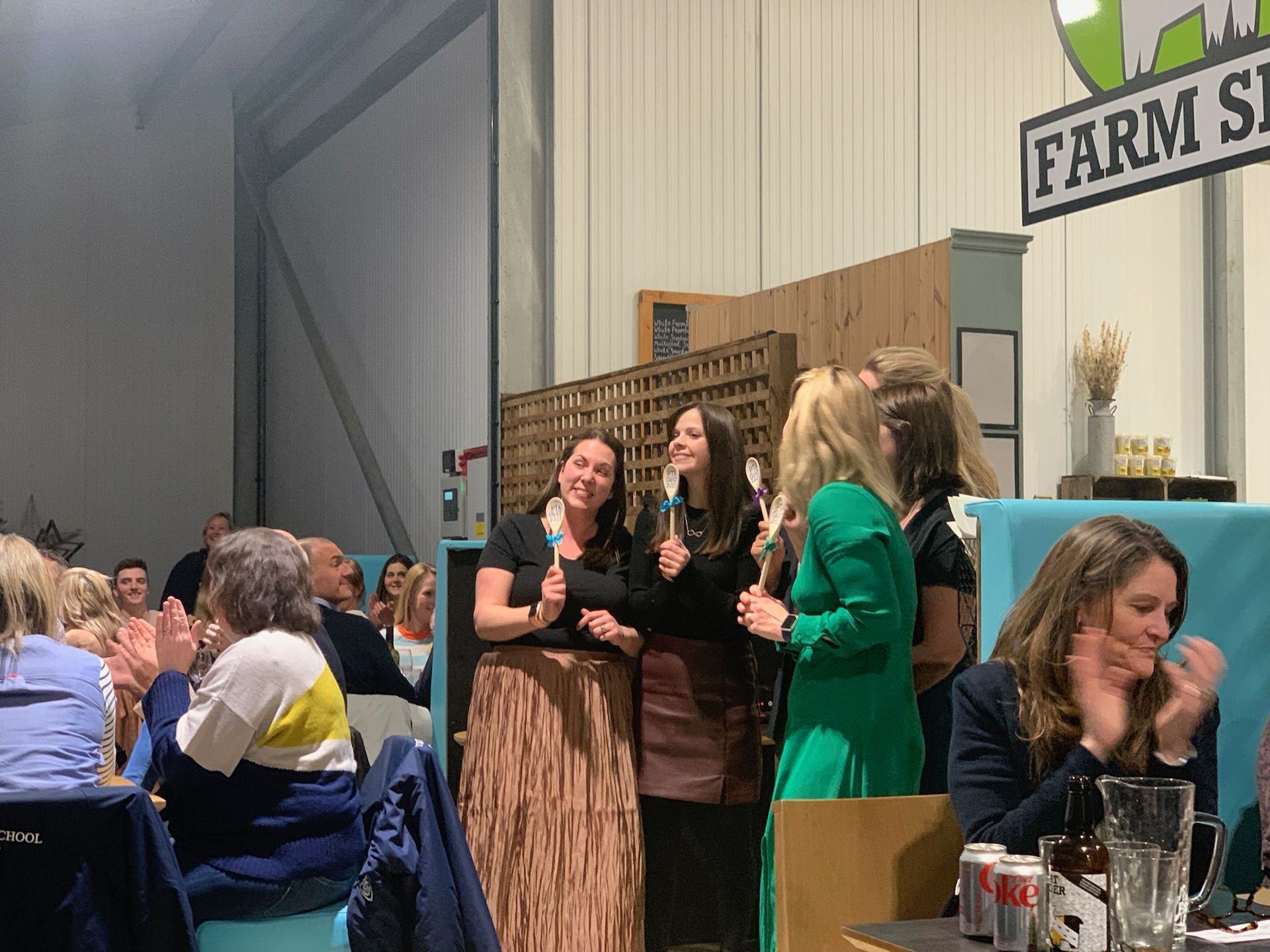 People applauding three women holding microphones at a 