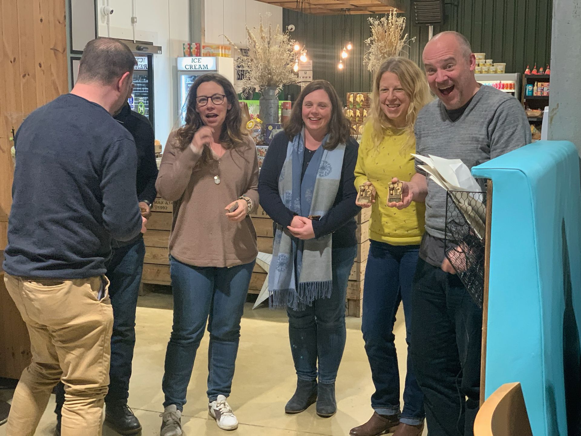 Group of five people indoors, smiling and looking surprised. One man is gesturing.