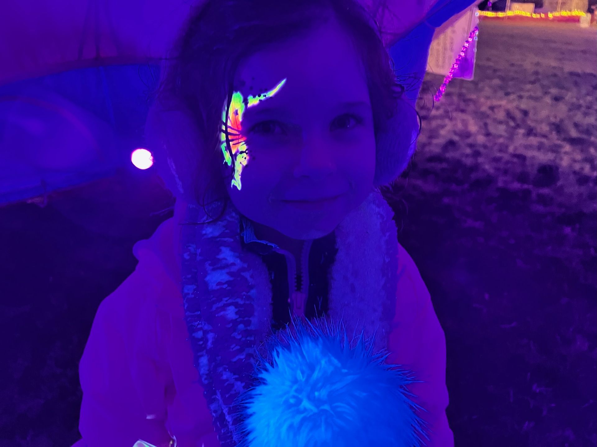 Girl with neon face paint under blacklight.