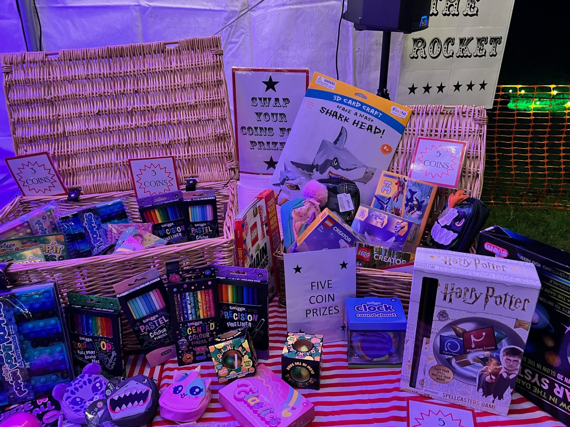 A gift basket with books, pens, and toys on a red and white striped surface.