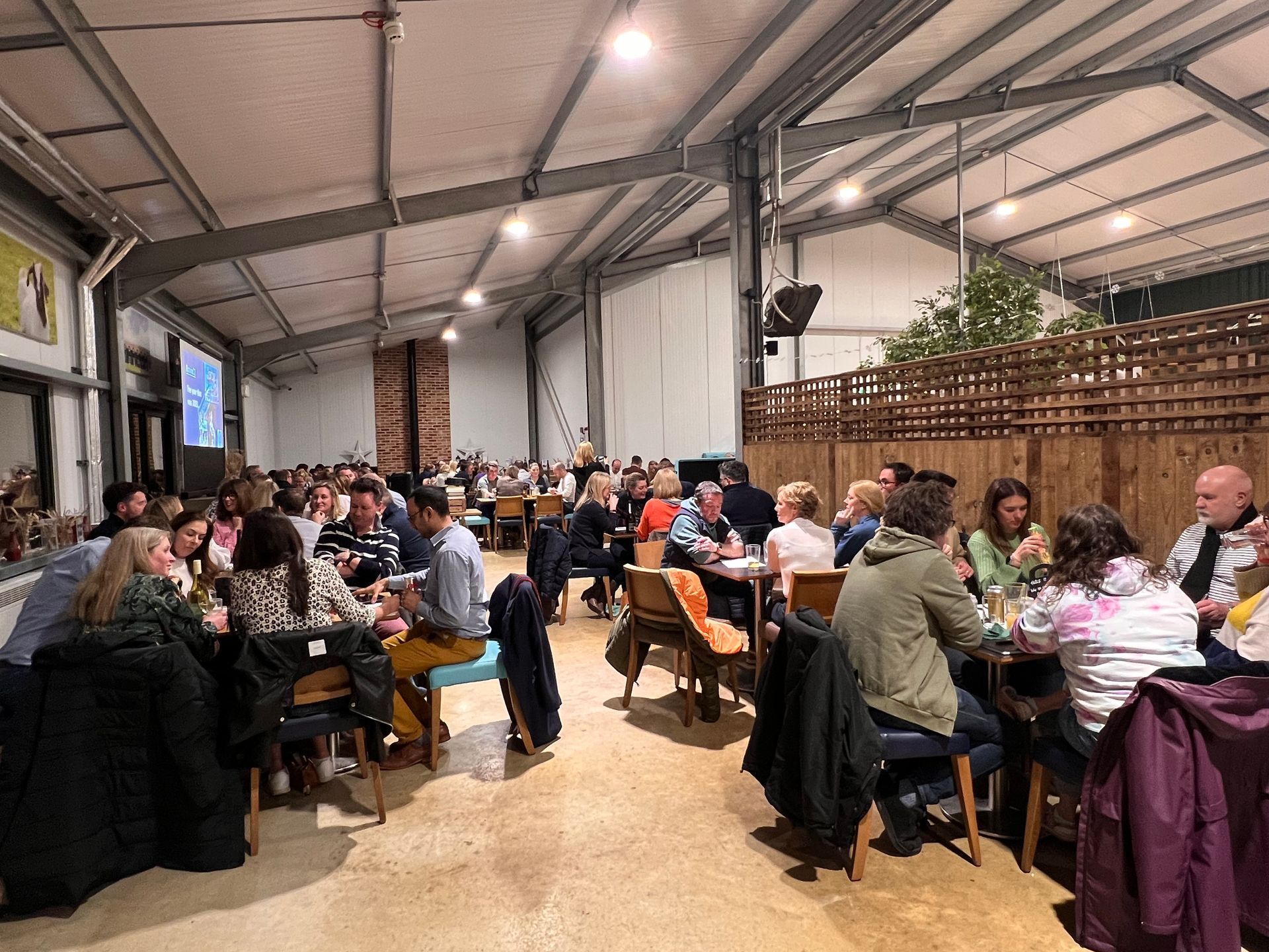 Large event space with people seated at tables, enjoying food and drinks.