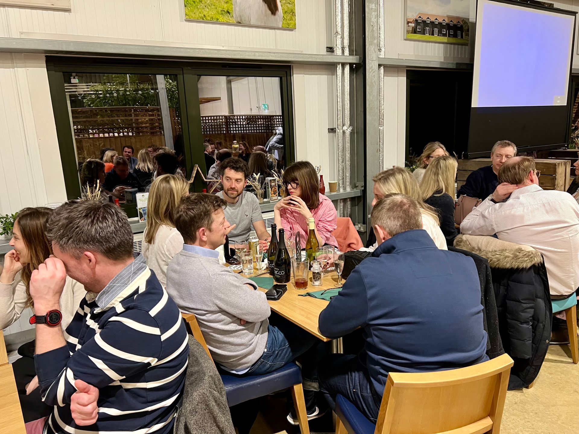People gathered around a table in a well-lit room, socializing and enjoying a meal.
